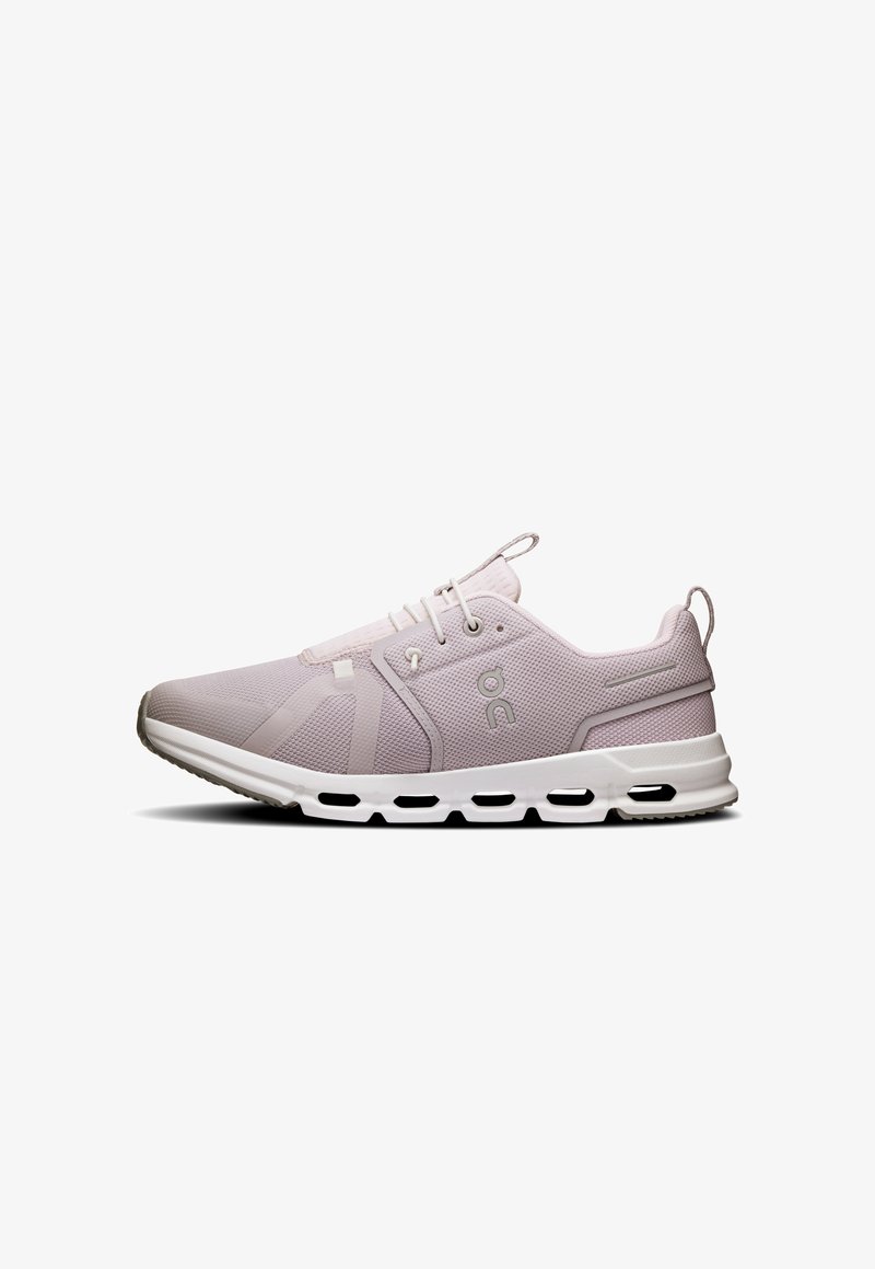 Chaussure de sport mauve clair avec tige en mesh, semelle intermédiaire blanche et accents noirs. Présente un design minimaliste et une forme de bout arrondi.