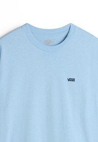 Světle modré bavlněné tričko s kulatým výstřihem a krátkými rukávy. Obsahuje malé černé logo "VANS" na levé straně hrudi. Měkká textura.