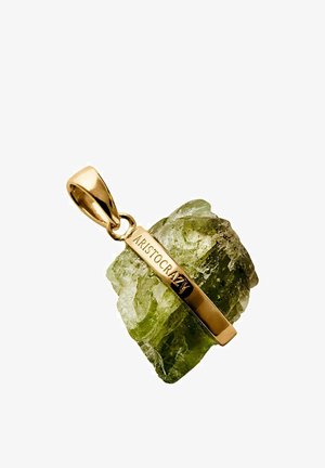 Colgante de oro grabado con "ARISTOCRAZY" que encierra una piedra preciosa verde, rugosa y translúcida con superficie texturizada.
