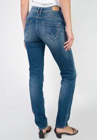 Jeans ajustados en denim azul oscuro, con una cintura alta, dos bolsillos traseros con un diseño distintivo y efectos de desvanecimiento sutil.