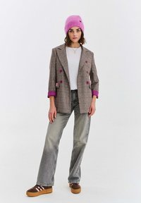 Kárované sako s fialovými doplnkami a gombíkmi, v kombinácii s bielym topom, sivými džínsami s širokými nohavicami a hnedými platformovými teniskami. Ružová čiapka.