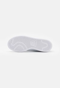 Suola di scarpa sportiva bianca con texture esagonale, bordi lisci e logo del marchio. Progettata per aderenza e durabilità.