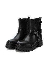 Botas de tobillo de cuero negro con cremallera lateral, detalles de hebilla y una suela gruesa y robusta con profundos surcos para un mejor agarre.