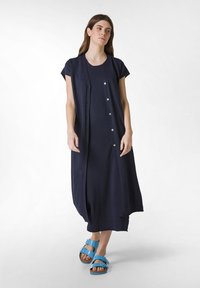 Mörkblå stickad klänning med korta ärmar, knapplåsning framtill och en avslappnad passform, tillsammans med blå justerbara sandaletter.