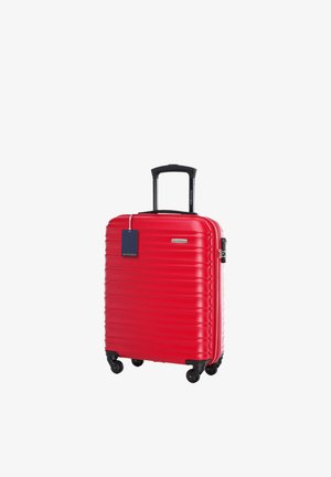Czerwona twarda walizka z czterema czarnymi obracającymi się kółkami, czarną teleskopową rączką, bocznym zamkiem i niebieską metką na bagaż.
