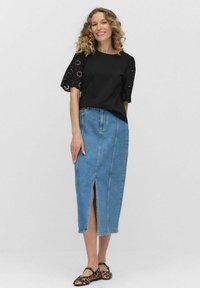 Czarna bluzka z misternymi koronkowymi rękawami, zestawiona z jasnoniebieską spódnicą dżinsową z przednim rozcięciem. Nosi się ją z czarnymi i brązowymi balerinami w panterkę.