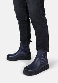 Dunkelblaue Knöchelstiefel mit einer glatten Lederoberfläche, kontrastierenden gestreiften elastischen seitlichen Einsätzen und dicken Gummisohlen.