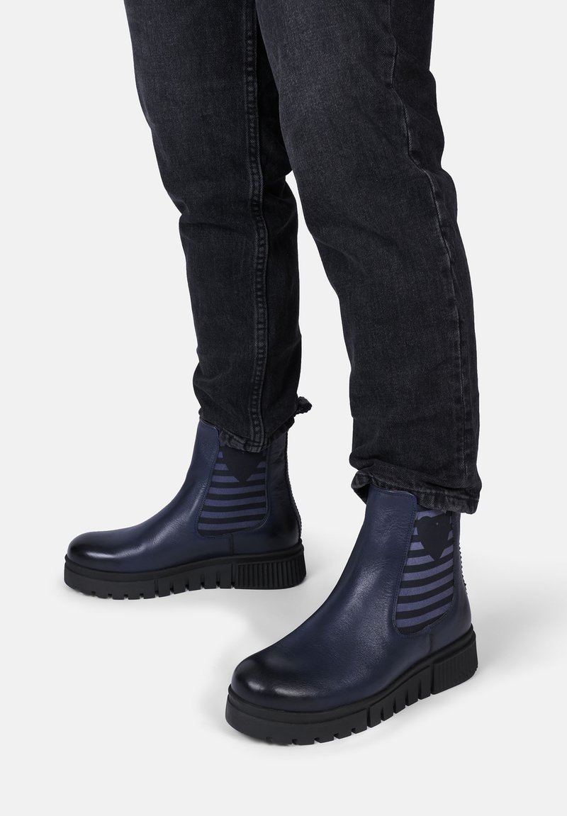 Dunkelblaue Knöchelstiefel mit einer glatten Lederoberfläche, kontrastierenden gestreiften elastischen seitlichen Einsätzen und dicken Gummisohlen.