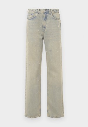 Svijetloplave široke traperice s izblijedjelim završetkom, ukrašene srebrnim zakovicama raspoređenim u kružne uzorke na prednjem dijelu.