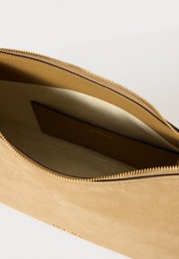 Beige nahka kassi, jossa on teksturoitu pinta, kultainen vetoketju ja ruskea sisus, varustettuna korttipussilla järjestämistä varten.
