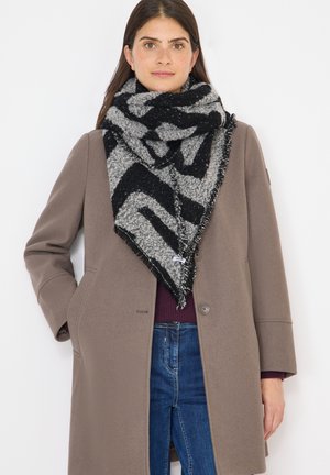 Écharpe à motifs noir et gris avec des bords effilochés, portée sur un manteau gris et un pull bordeaux, présentée sur fond blanc.