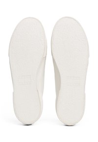 Semelles de baskets blanches avec des surfaces texturées ; logo rectangulaire « TOMMY JEANS » embossé sur le côté. Caoutchouc blanc lisse ; bords arrondis.