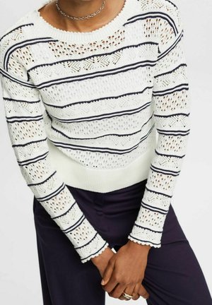 Pull en tricot blanc avec des rayures horizontales bleu marine, des motifs ajourés complexes, un col et des poignets côtelés, et un ourlet en scallop.