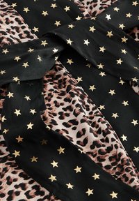 Tessuto nero con motivi di stelle dorate si sovrappone a un tessuto leopardato rosa, mettendo in mostra texture e design contrastanti.