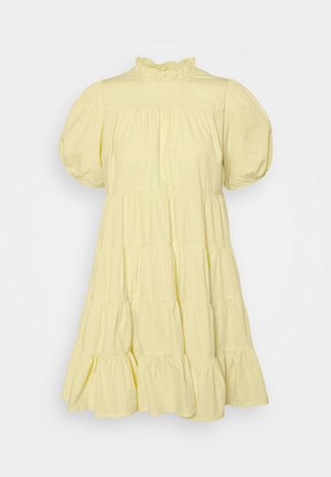 Żółta, warstwowa sukienka z bawełny z krótkimi bufkami, wysokim kołnierzem ozdobionym falbanką oraz luźną sylwetką zakończoną falbaniastym dołem.