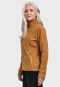 Fleecejacke in senfgelb mit hohem Kragen, Frontreißverschluss und seitlichen Taschen. Verfügt über dezente Markenkennzeichnung am Ärmel und eine glatte Textur.