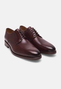 Ein Paar polierte dunkelbraune Lederhalbschuhe mit geschlossenen Schnürsenkeln, flachen Absätzen und glatten, abgerundeten Spitzen auf einem weißen Hintergrund.
