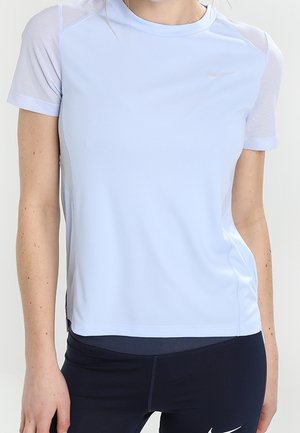 T-shirt de sport bleu clair à manches courtes avec des empiècements en mesh porté avec des leggings noirs Nike, visible du cou aux hanches.