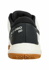Zapatilla deportiva en blanco y negro con un trasero texturizado, suela de goma y la marca "RUSHPRO ACE". Cuenta con un collar acolchado para mayor soporte.