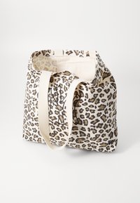 Plátěná taška s béžovým pozadím a hnědým leopardím potiskem. Obsahuje pevné krémové popruhy a minimalistické logo.