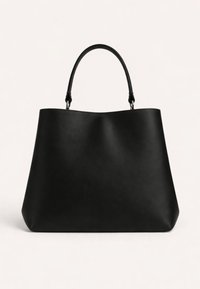 Μαύρη δερμάτινη τσάντα χειρός με μονό στρογγυλό χερούλι και μινιμαλιστικό σώμα σε σχήμα τραπεζίου, σε απλό φωτεινό φόντο.