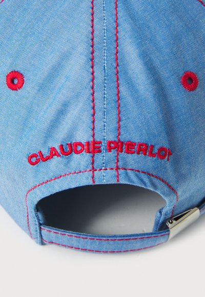 Cappellino azzurro chiaro con cuciture e occhielli rossi, con "CLAUDIE PIERLOT" ricamato in rosso sul retro. Dettaglio della chiusura regolabile visibile.