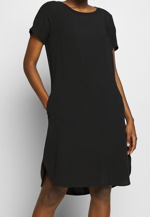 Robe noire à manches courtes avec un col rond, coupe décontractée et poches latérales. Tissu lisse avec un léger éclat et détail d'ourlet asymétrique.