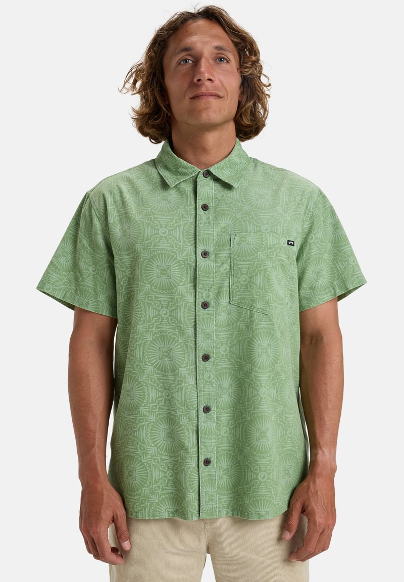 Chemise à manches courtes verte à boutons, ornée d'un motif géométrique intégral, d'une poche poitrine et de boutons foncés. Fabriquée dans un tissu léger.