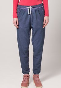 Blå smale joggebukser med snøring i midjen, laget av myk stoff, med en lett teksturert overflate og elastiske mansjetter.