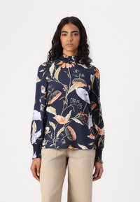 Blusa floreale in tessuto blu navy con maniche lunghe a sbuffo, colletto alto arricciato e una vivace stampa botanica in tonalità di rosa e giallo.