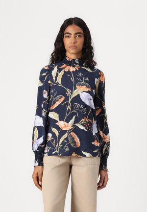Blumenbluse aus marineblauem Stoff mit langen Puffärmeln, einem gerafften hohen Kragen und einem lebendigen botanischen Druck in rosa und gelben Farbtönen.