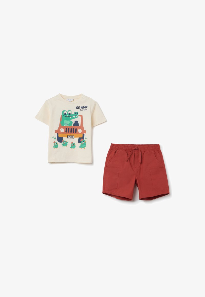 Cream t-shirt featuring a colorful frog graphic and text, paired with red shorts with pockets, made of lightweight fabric.