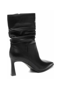 Čierne kožené členkové čižmy so splývavým dizajnom, špicatou špičkou a 7,5 cm vysokým stiletto podpätkom. Majú hladkú textúru a diskrétny zips.