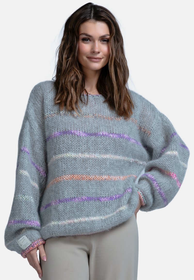 Szary, oversize sweter z miękkim, teksturowanym splotem, zdobiony wielokolorowymi poziomymi paskami w różowych, fioletowych i pomarańczowych akcentach.