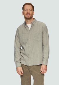Grijs herringbone-patroon overhemd met knopen, voorzien van twee borstzakken en een kraag. Draag het over een wit t-shirt, gecombineerd met ribfluwelen broek.