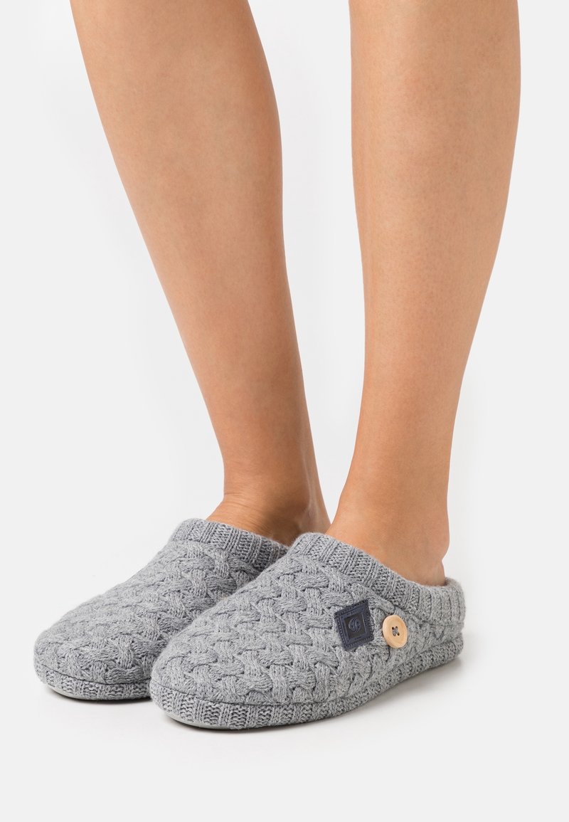 Les chaussons tricotés gris présentent un motif torsadé texturé, un col doux et un bouton en bois décoratif sur le côté.