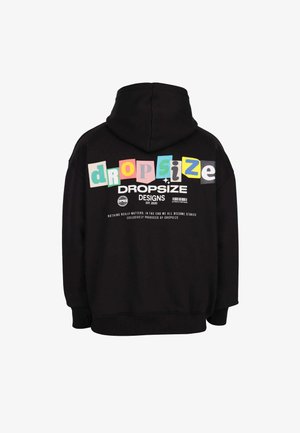 Mustmust tülikapp, millel on värvilised "dropsize" tähed ja valge tekst "DROPSIZE DESIGNS EST. 2020" ning silt seljas.