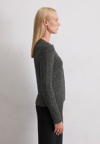 Pullover lavorato a maglia di un grigio scuro con un motivo testurizzato, scollo rotondo e polsini a coste. Vestibilità slim con un orlo leggermente più corto.