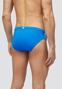 Bañadores breves en vibrante tejido azul, con una textura suave y un acento en verde neón. Diseño de talle bajo con un ajuste seguro en la cintura.