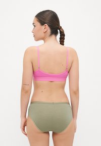 Ružový bavlnený bralet s nastaviteľnými ramienkami, spárovaný s olivovo zelenými bavlnenými hipster nohavičkami. Hladká textúra, minimalistický dizajn, bez vzorov.