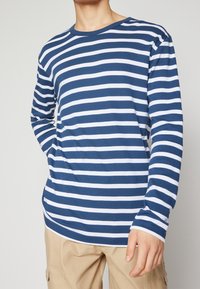 Blau-weiß gestreiftes Langarm-T-Shirt mit rundem Ausschnitt und lässiger Passform, aus weichem Baumwollstoff gefertigt.