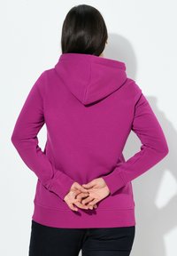 Felpa fucsia con cappuccio, maniche lunghe e orlo a bordo, dotata di tasca a marsupio e texture liscia.