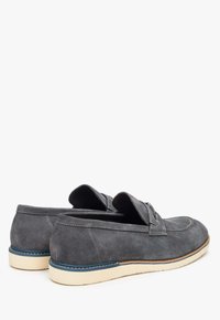 Graue Wildleder-Loafers mit niedrigem Profil, hellfarbiger Gummisohle und dezenten Nähdetails entlang der Oberseite und Seiten.