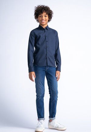 Marine knop-overhemden met een kraag, gecombineerd met blauwe jeans en witte sneakers. Het overhemd heeft een gestructureerde stof en een rechte snit.