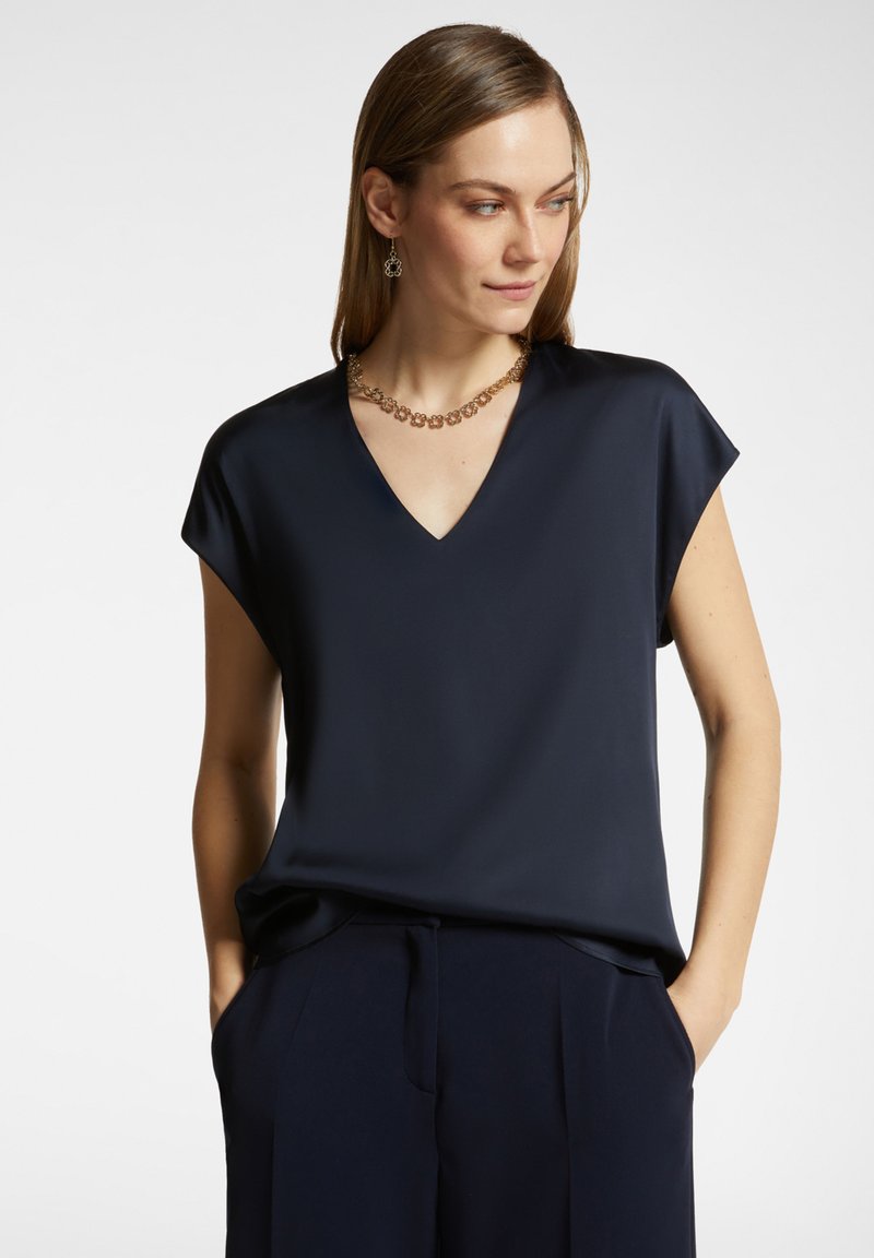 Top corto navy a maniche corte con scollatura a V, realizzato in tessuto morbido. Caratterizzato da una vestibilità ampia e una leggera caduta dell'orlo. Adatto per abbigliamento casual o formale.