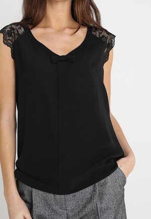 Schwarzes ärmelloses Oberteil mit Spitzendetails an den Schultern, V-Ausschnitt, Schleifendetail in der Mitte und einem glatten, fließenden Stoff.