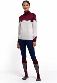 Maglione a collo alto lavorato a maglia in bordeaux e bianco con righe blu navy, abbinato a leggings aderenti blu navy e calzini rossi e grigi fino al ginocchio.