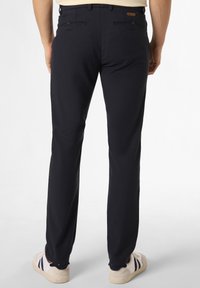 Granatowe chinosy z teksturowanej tkaniny, o zwężanym kroju nogawki, z dwiema tylnymi kieszeniami, połączone z jasnymi trampkami.