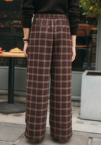 Pantaloni a gamba larga a quadri prugna con vita elastica e tasche posteriori, caratterizzati da linee beige e verde scuro in un tessuto morbido.
