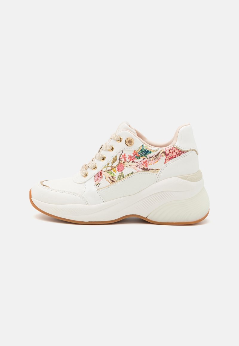 Baskets blanches avec semelle épaisse et panneau en tissu floral avec des fleurs roses et vertes sur le côté, lacets beiges et semelle extérieure couleur gomme.